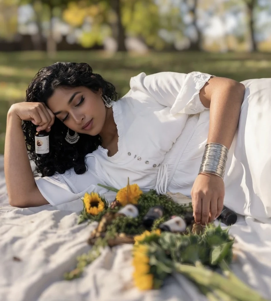 Founder of Ammi's Essence resting beside handmade hair oils in a sunlit park