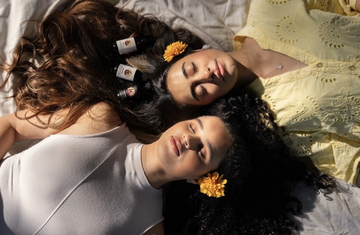 Two women resting together with Ammi's Essence oils in their hair